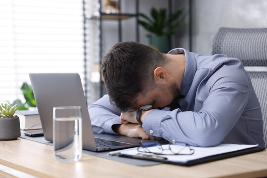 Man feeling fatigue at wooden desk in office