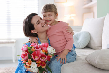 Happy Mother's Day. Mom and her daughter with bouquet of beautiful flowers at home