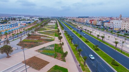Aerial drone view of a newly renovated modern avenue featuring green public parks, sports courts, palm trees, and urban infrastructure in Agadir, Morocco. © Lahoucine