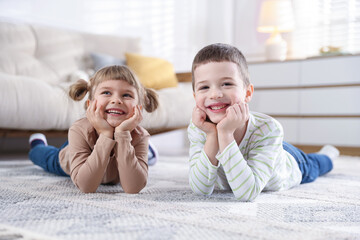 Little brother and sister spending time together on floor indoors