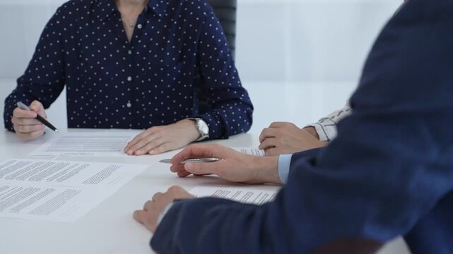 Corporate professionals analyzing contract details, gesturing toward key points while negotiating partnership terms in modern office boardroom