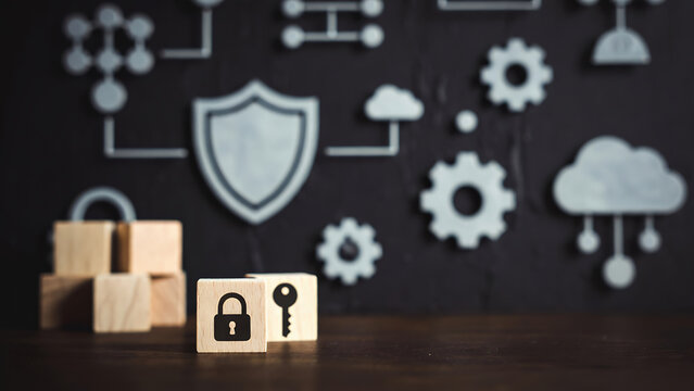 Wooden blocks with lock and key icons positioned on a table against a background of blurred security diagrams.