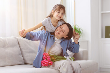 Obraz premium Happy Mother's Day. Little girl and her mom with beautiful flowers on sofa indoors