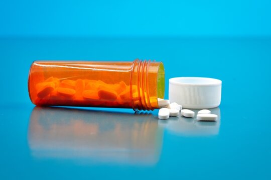 Medication White Pills and  Orange Plastic Container Blue Background 