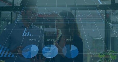 Discussing data, colleagues in business attire gesturing toward tablet in modern office with charts