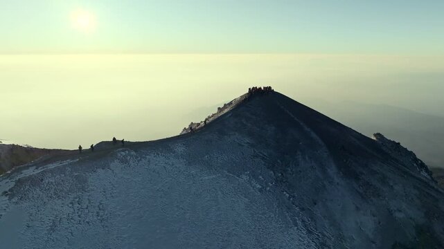 Aerial view of the top  snow covered summit of Pico de Orizaba, also known as Citlaltepetl, the highest volcano in Mexico with mountaineers climbing on the top. Captured in cinematic 4K perspective