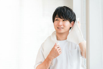 Young Asian man towel drying his hair after shower