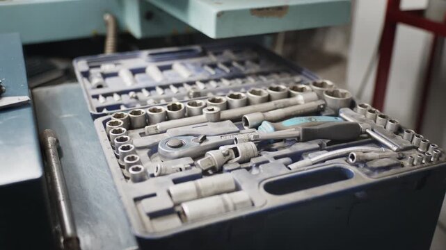 Slow pan of aprofessional socket and ratchet wrench set resting in a blue case in a workshop
