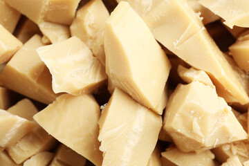 Fototapeta premium Pieces of natural cocoa butter as background, closeup
