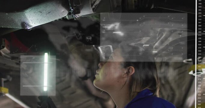 Female tech holding LED light and scanning car underside, HUD panels growing and aiding diagnosis
