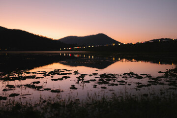Naklejka premium Lake reflecting twilight sky and distant city lights