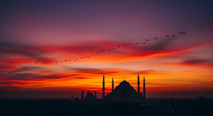 Fototapeta premium Silhouette of a Grand Mosque at Sunset with a Long V-Shaped Formation of Birds Flying Across a Vibrant Orange and Purple Evening Sky Islamic Architecture Landscape