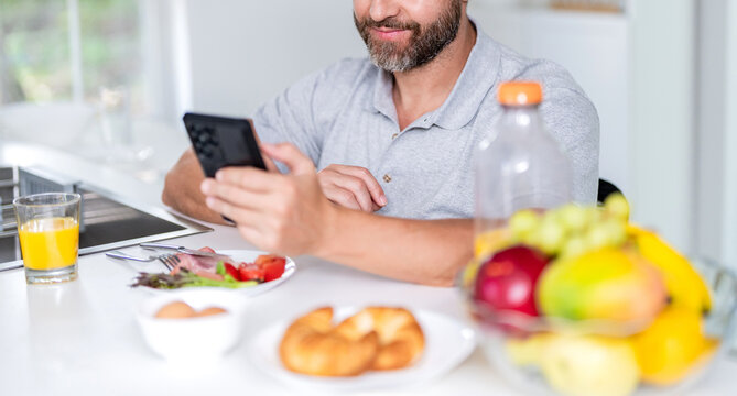 Man cropped view eating cereal with milk. Healthy food online. Man eat morning breakfast in kitchen. Business man eating morning breakfast. Morning at home with phone. Breakfast in kitchen