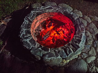 Naklejka premium Night photo of bonfire in stone fire pit. Flame of burning wood in camp at night.