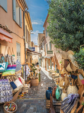 LE LAVANDOU, FRANCE - SEPTEMBER 30, 2025: Souvenir shops line a narrow pedestrian lane in Le Lavandou, Provence, France, with baskets, beach bags and local products in a French Riviera village.