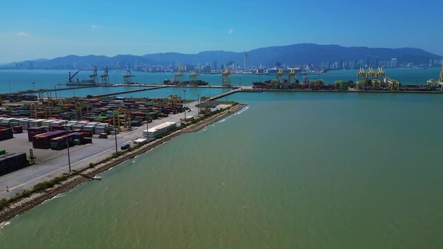 Busy container port with stacks of shipping containers and gantry cranes, representing global trade and logistics. Beautiful aerial view fly reverse drone