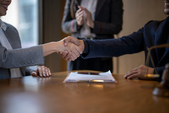 Professionals shaking hands confirming business agreement with contract