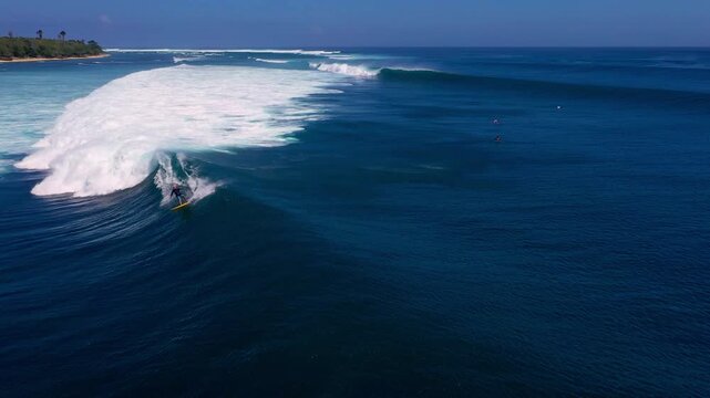 Active Male Surfer Riding Huge Blue Barrel Wave in Crystal Clear Ocean Water. Tropical Island Coastline Surfing of Indonesia at Sunny Summer Day Vacation Trip for Extreme Sports Adventure Lifestyle 4k