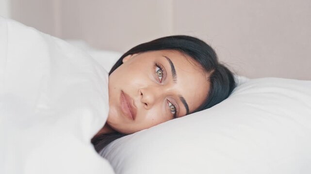 Attractive Female Face With Healthy Glowing Skin Smiling. Adult Girl Gently While Lying on White Pillow. Young Woman During Morning Wake Up Routine at Home Slow Motion 4k