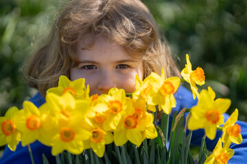 Naklejka premium Spring fun for kids. Child play outdoors in a beautiful spring garden. Kid face in flowers. Adorable little kid in blooming cherry garden on beautiful spring day. Happy child during spring blossom.