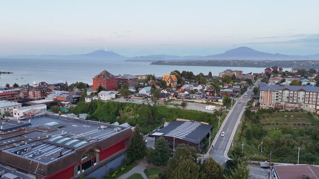 Cinematic aerial moving forward over downtown Puerto Varas and the Church of the Sacred Heart toward the expansive Lake Llanquihue and the snow-capped Osorno Volcano in Chile
