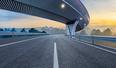 Naklejka premium Empty asphalt highway leading to karst mountain peaks at sunset in Guilin, Guangxi, China.