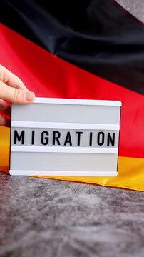 Lightbox with text MIGRATION flow. National symbol of Germany. German wave silky flag background. Concept of human migration crisis and population refugee movement. Demographic change 