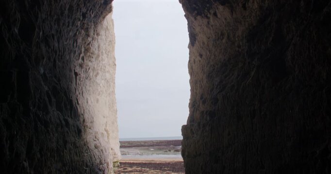 Tilting up shot looking out of a cave in chalk cliffs at Kingsgate beach bay. At low tide