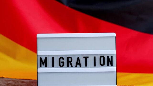 Lightbox with text MIGRATION flow. National symbol of Germany. German wave silky flag background. Concept of human migration crisis and population refugee movement. Demographic change 