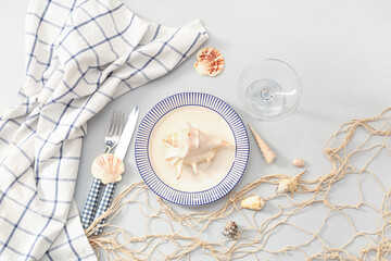 Beautiful table setting with seashells and net on grey background