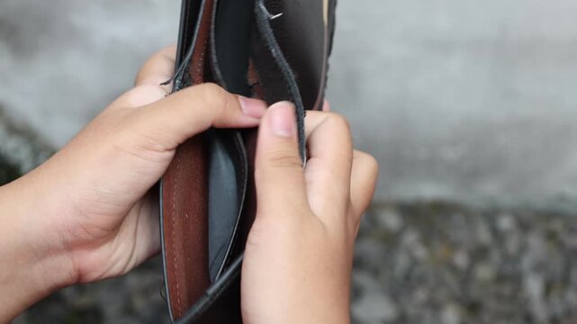 A man opens a wallet and finds out that the wallet has no money in it and is totally empty
