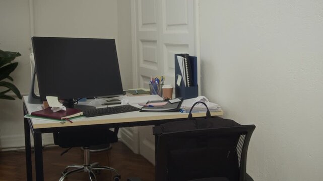 Medium long shot of modern workplace with computer, documents, folders, notebooks and office supplies on table and chair, no people