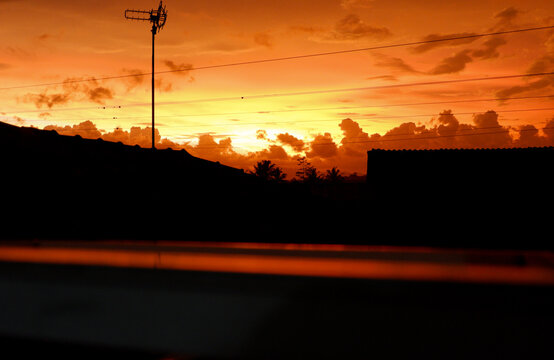Orange Sunset Sky with Silhouette of Rooftops and TV Antenna