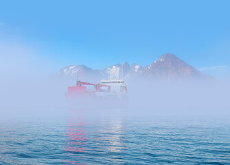 Arctic ship leaving Tasiilaq after having unloaded at the docks in the harbour fog in the background - Tasiilaq, Greenland © muratart