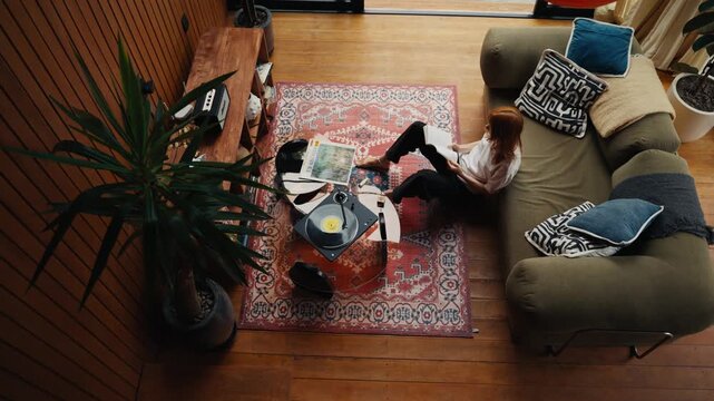 Woman relaxing reading a book while listening to music on a vinyl record player