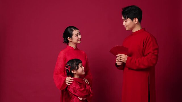 Father handing a red envelope to his daughter while the mother watches with a smile, warm Asian family moment celebrating Lunar New Year traditions.