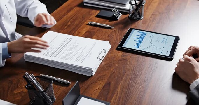 Business meeting between a doctor and a client discussing medical documents with charts