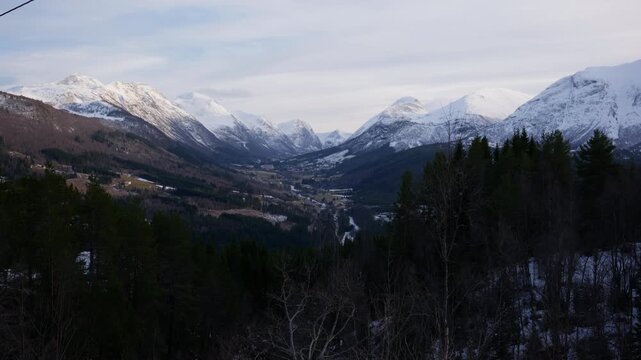 Scenic shot of Stranda dalen, a valley in Norway with tall mountains covered with snow on a bright winter day
