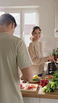 Young couple cooking a plant-based meal in a modern kitchen &mdash; joyful home cooking, vertical footage