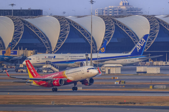30-01-2026, Bangkok Thailand, VietJet Air plane lands airport with backdrop of modern terminal architecture and another airplane background. scene captures dynamic and bustling 