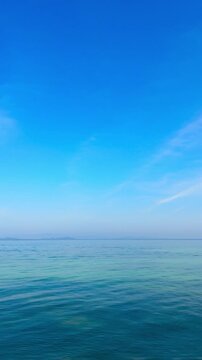 Vertical video of nature tropical and clear sky and summer sea water under a clear blue sky with beautiful clouds and bright sunlight. Perfect for summer vacation and travel background