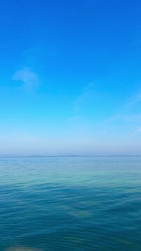 Vertical video of nature tropical and clear sky and summer sea water under a clear blue sky with beautiful clouds and bright sunlight. Perfect for summer vacation and travel background