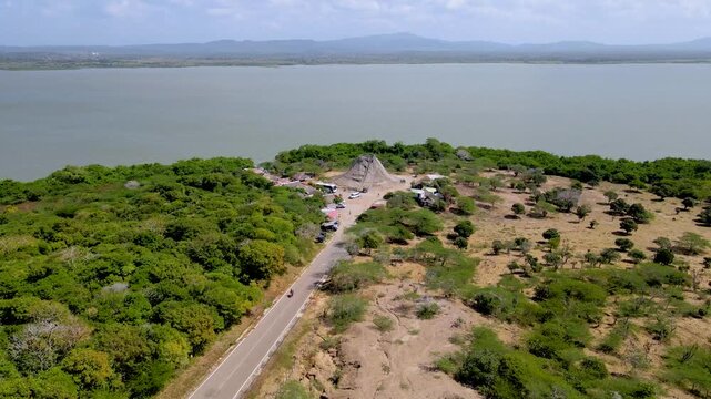Overhead shot showing Totumo Volcano amid vibrant trees and expansive lake during a clear day.