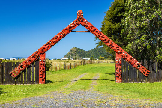 Traditional Maori carvings on a wooden gateway, or waharoa, at a marae in Kennedy Bay, New Zealand