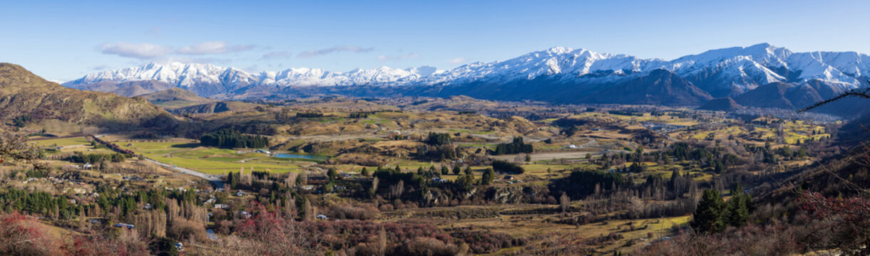 Panoramic view from the Crown Range, Otago, New Zealand. To the right, the settlement of Arrowtown sits at the base of the Southern Alps