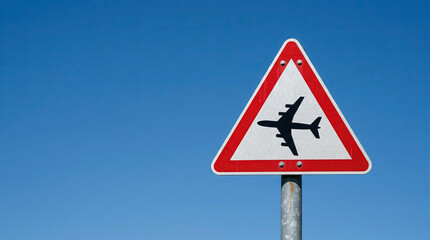 Airplane Crossing Warning Road Sign Against Blue Sky