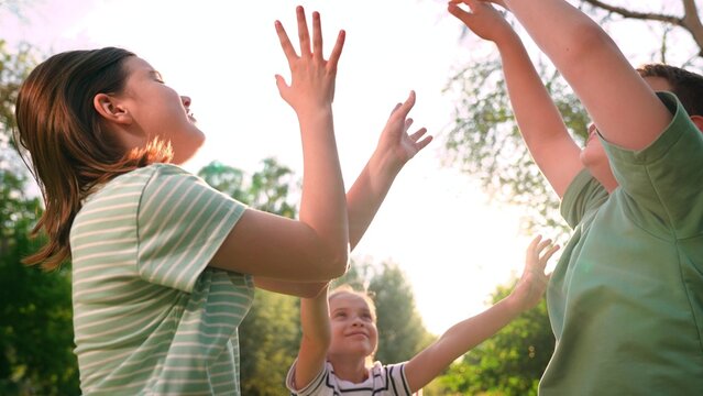 Happy children playing playground, children hands sun glare nature, boy girl friends playground, outdoor kids teamwork and social play, playful kids circle game in summer greenery, sunny day activity