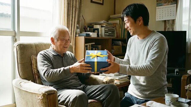 膝をついて高齢の父に優しくプレゼントを渡す成人の息子