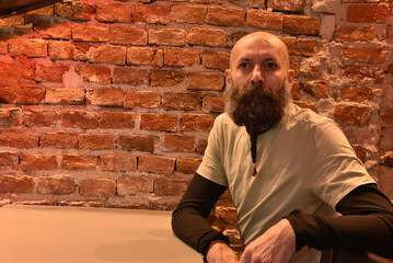 Bald man with a long braided beard looking away in a rustic setting