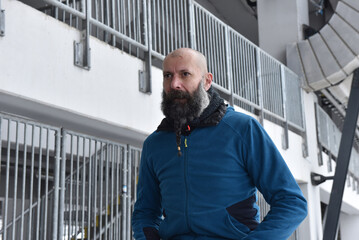 Bearded bald man in blue fleece zip jacket by metal railings © salajean